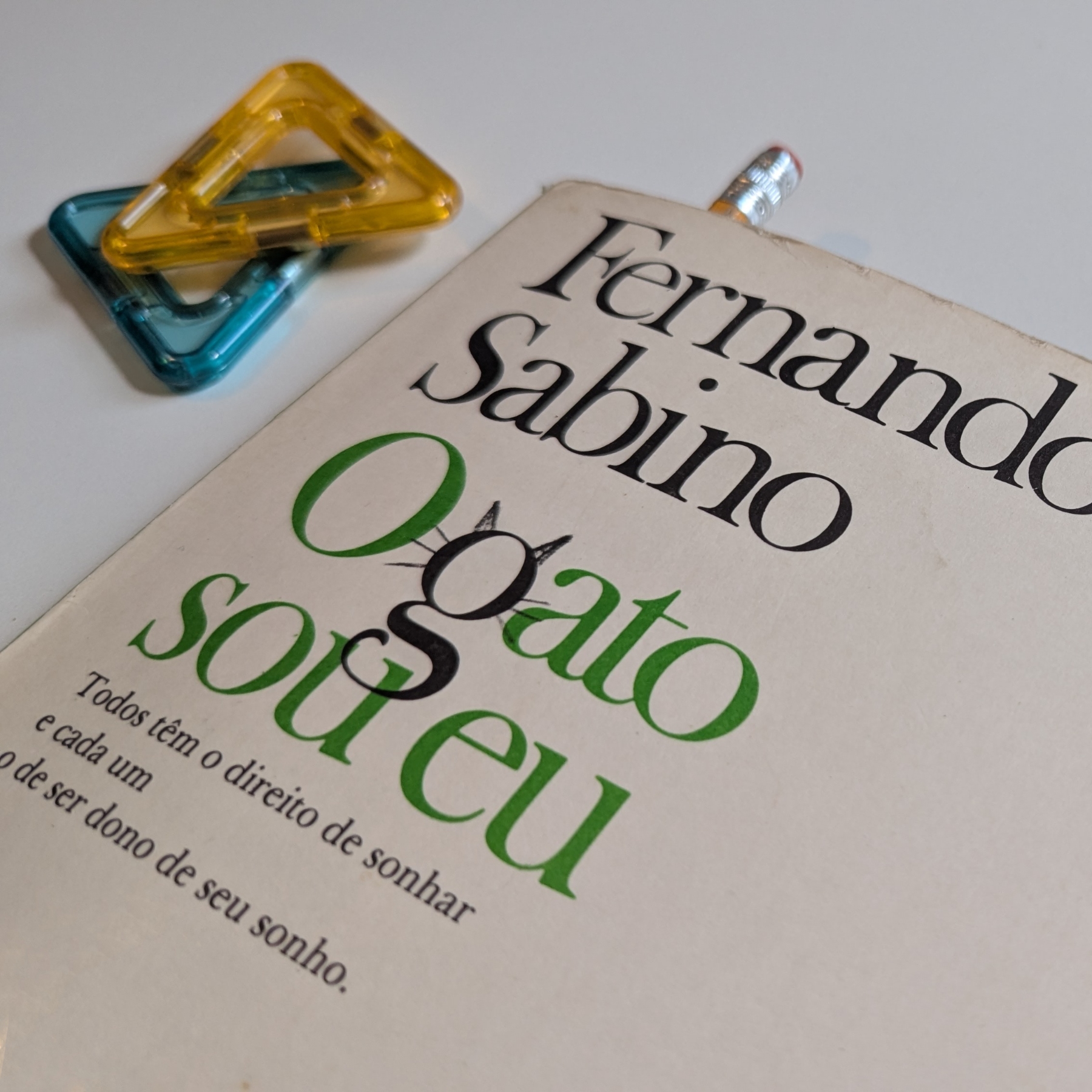 Livro O Gato sou eu em cima de uma mesa e com um lápis dentro funcionado como marcador de página
