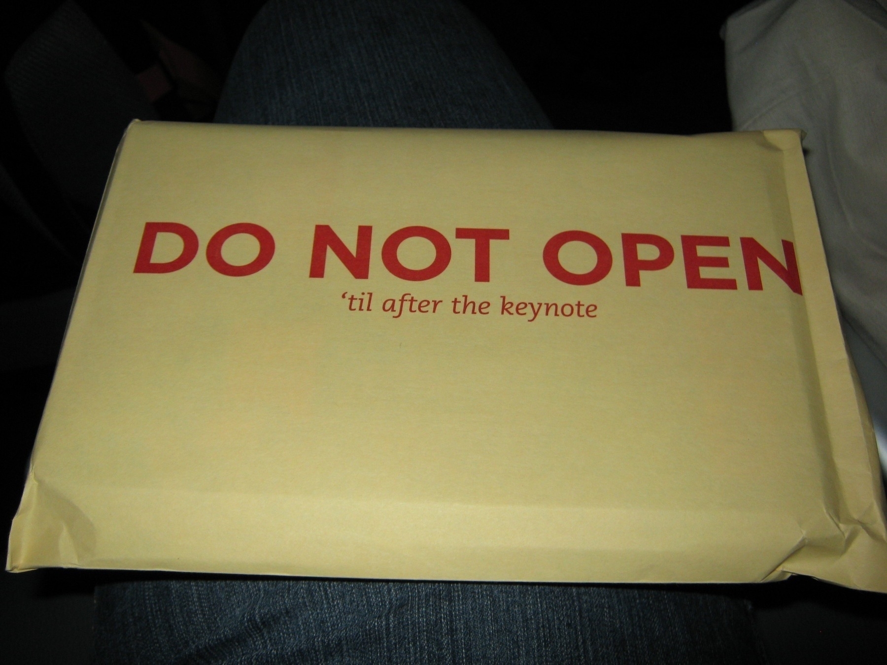 A sealed envelope with the text DO NOT OPEN 'til after the keynote is placed on someone's lap.