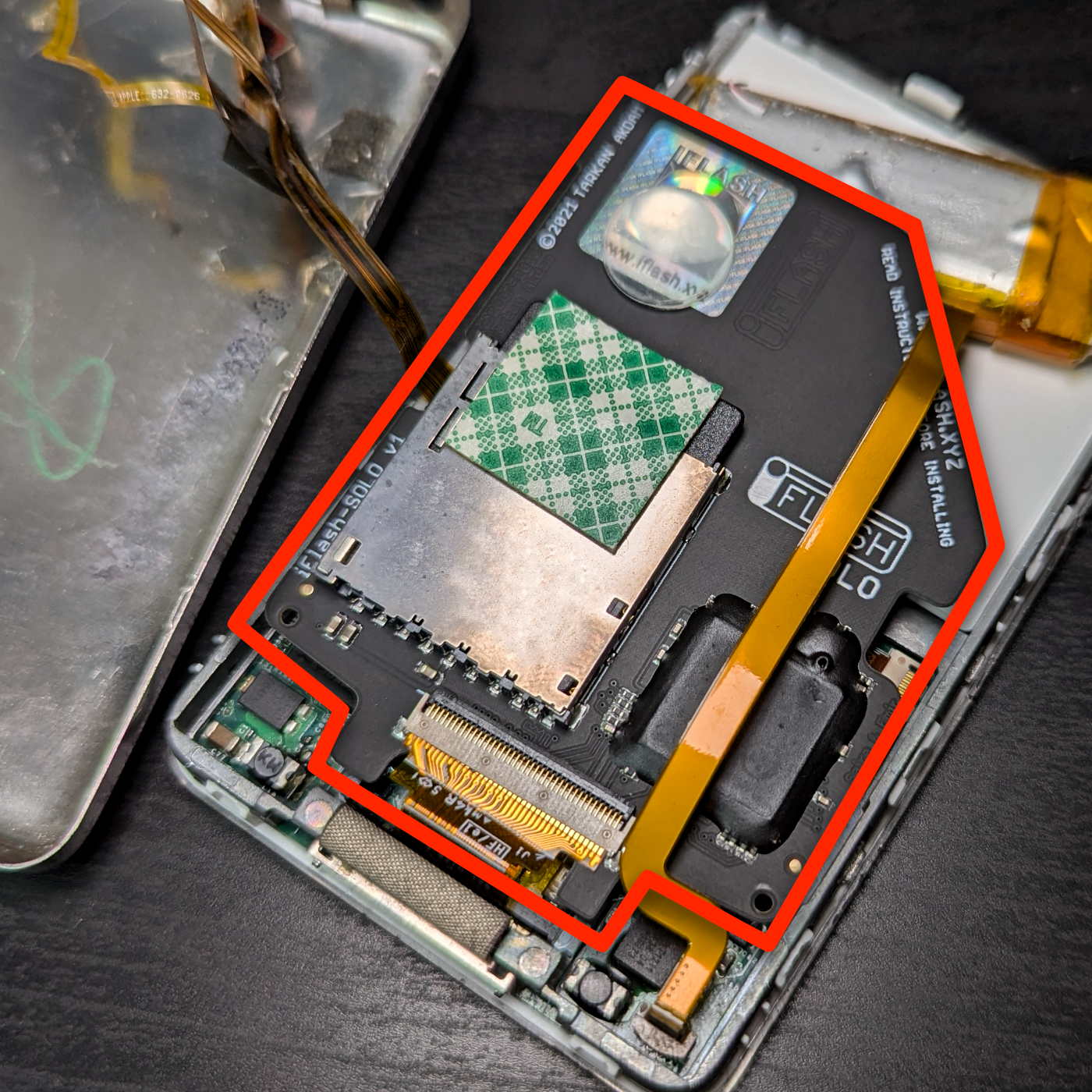 An open iPod reveals its internal components, including a circuit board and connectors, with a focus on a section labeled iFlash.